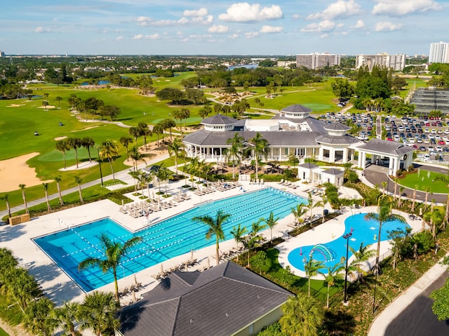 community pool with view of golf course, a patio, and fence