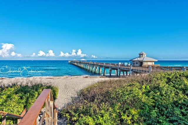 view of dock with a pier, a view of the beach, and a water view