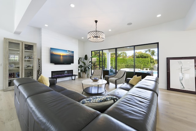 living area featuring a notable chandelier, a large fireplace, recessed lighting, and light wood-style floors