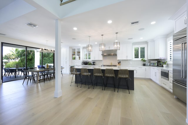 kitchen featuring tasteful backsplash, stainless steel built in refrigerator, visible vents, and a kitchen breakfast bar