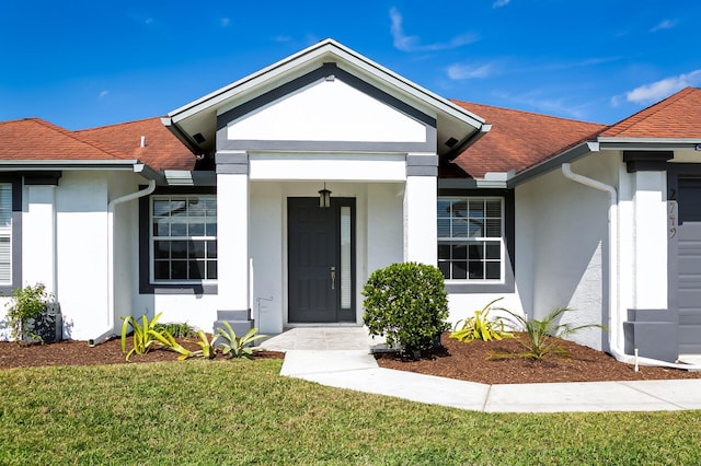 2749 SW Backton Ave, Port Saint Lucie, FL 34987 - property entrance featuring stucco siding, a yard, and a shingled roof