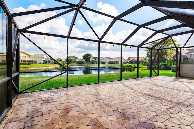 view of patio / terrace with a water view, glass enclosure, and a residential view