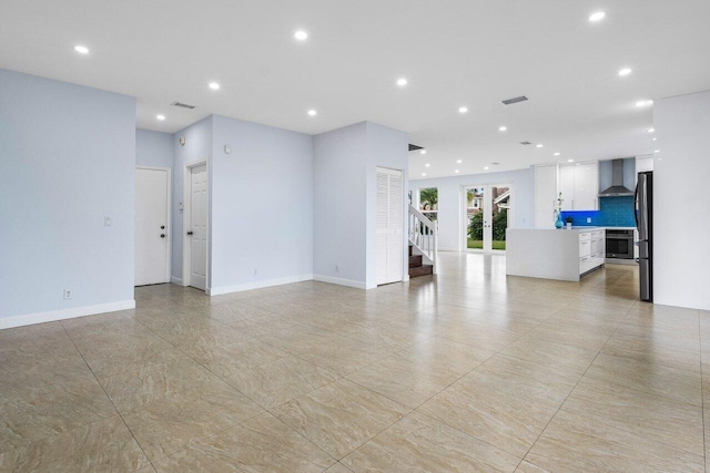 unfurnished living room featuring baseboards, stairs, visible vents, and recessed lighting