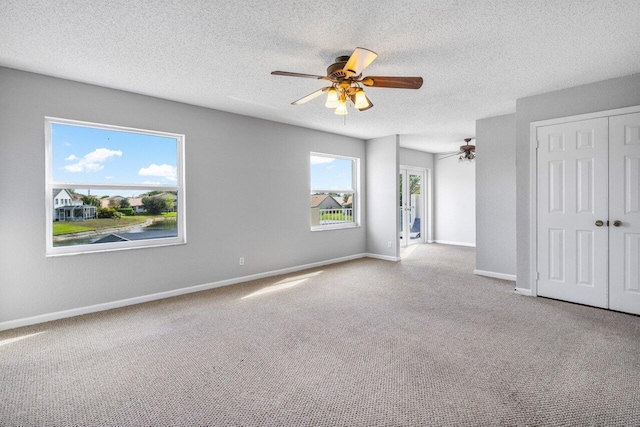 unfurnished bedroom featuring a textured ceiling, carpet floors, a ceiling fan, baseboards, and a closet