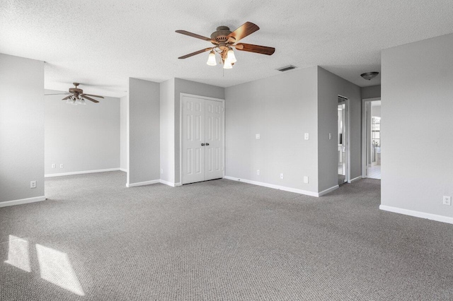 carpeted empty room with baseboards, a textured ceiling, visible vents, and a ceiling fan