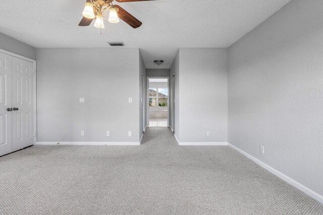 unfurnished bedroom featuring baseboards, a textured ceiling, visible vents, and light colored carpet