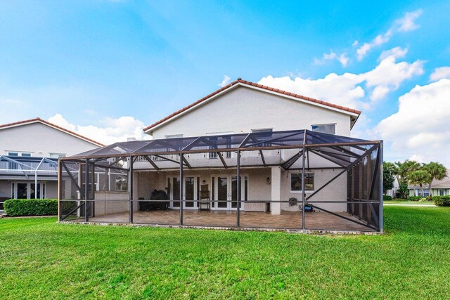 back of house with glass enclosure, a yard, a patio area, and stucco siding