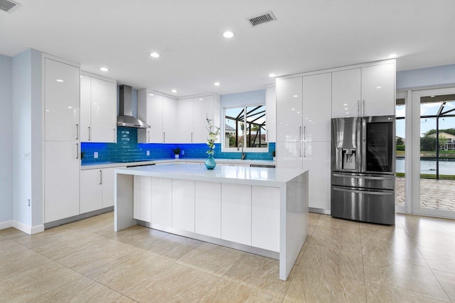 kitchen featuring stainless steel fridge, visible vents, white cabinets, light countertops, and wall chimney range hood