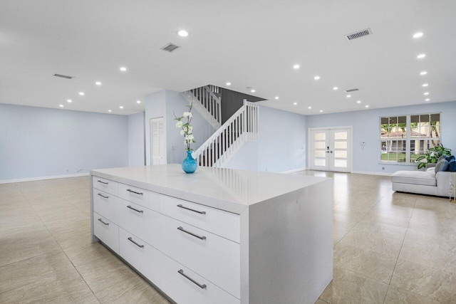 interior space with white cabinets, a spacious island, modern cabinets, open floor plan, and light countertops