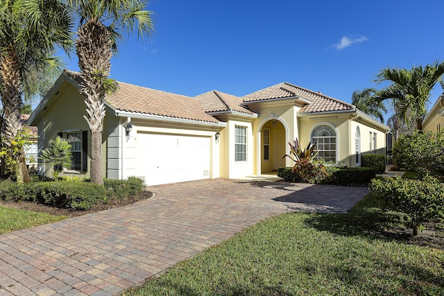 mediterranean / spanish house featuring a garage and a front lawn