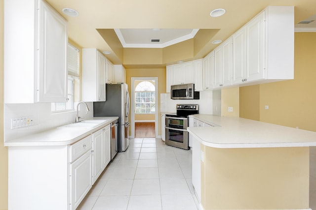 kitchen featuring ornamental molding, kitchen peninsula, white cabinets, and appliances with stainless steel finishes