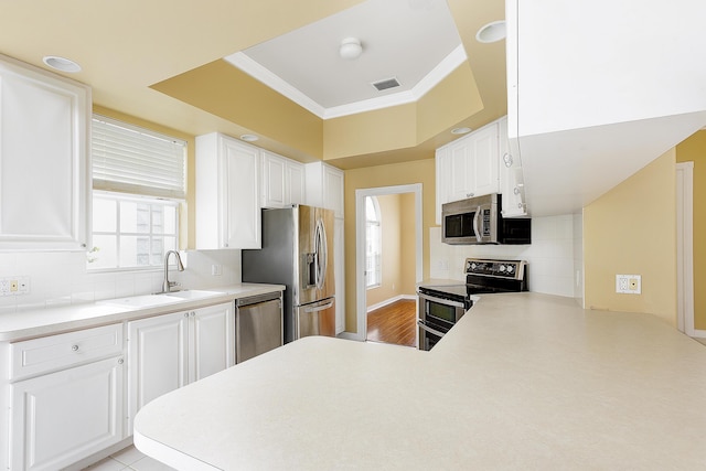 kitchen featuring sink, appliances with stainless steel finishes, backsplash, white cabinets, and kitchen peninsula