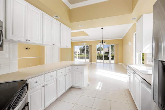 kitchen with stainless steel appliances, white cabinetry, ornamental molding, and decorative light fixtures