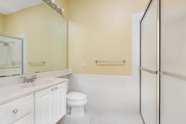 bathroom featuring a shower with shower door, tile walls, vanity, toilet, and tile patterned floors