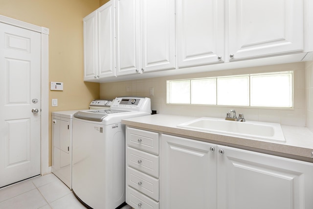 laundry area featuring a wealth of natural light, separate washer and dryer, sink, cabinets, and light tile patterned floors