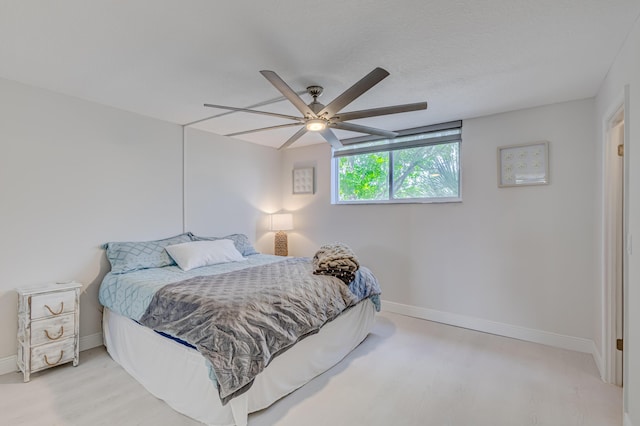 bedroom featuring ceiling fan, a textured ceiling, baseboards, and wood finished floors