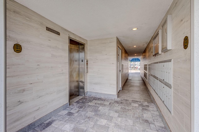 hall with a textured ceiling, recessed lighting, mail area, and elevator