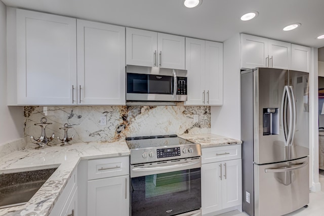 kitchen with light stone counters, appliances with stainless steel finishes, backsplash, and white cabinetry