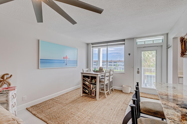 interior space with a ceiling fan, a textured ceiling, and baseboards