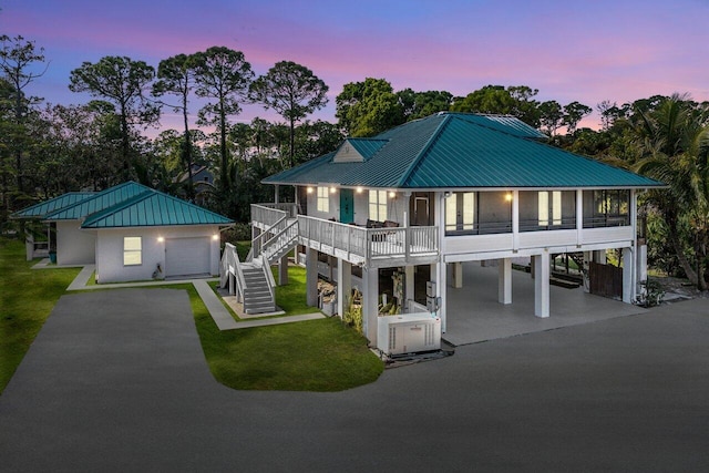 exterior space with a garage, a porch, a carport, and a lawn