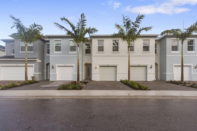 townhome / multi-family property with a garage, driveway, and stucco siding