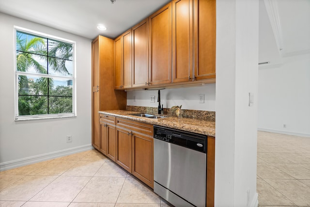 kitchen featuring stainless steel dishwasher, light stone countertops, sink, and light tile patterned floors