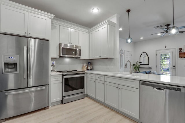 kitchen featuring decorative light fixtures, white cabinetry, sink, light hardwood / wood-style floors, and stainless steel appliances