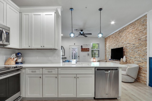 kitchen featuring sink, hanging light fixtures, stainless steel appliances, white cabinets, and kitchen peninsula