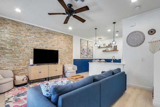 living room featuring crown molding, ceiling fan, bar, and light hardwood / wood-style flooring