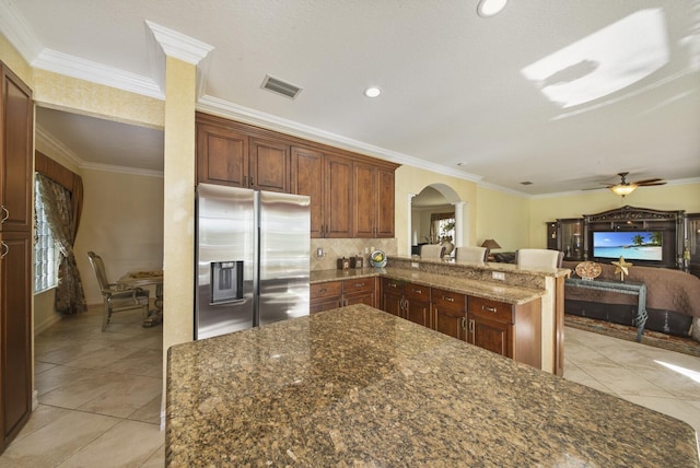 kitchen with visible vents, stainless steel fridge with ice dispenser, ornamental molding, decorative columns, and arched walkways