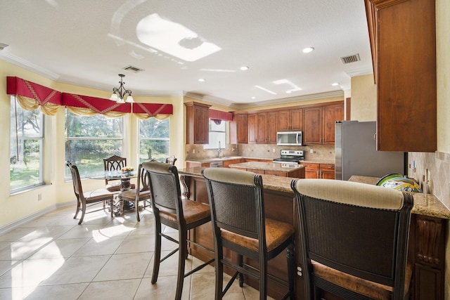 kitchen with decorative backsplash, crown molding, visible vents, and stainless steel appliances