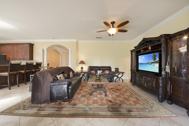 living area with crown molding, decorative columns, light tile patterned flooring, arched walkways, and a ceiling fan