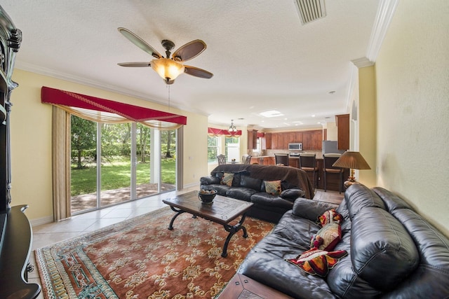 living area with baseboards, visible vents, light tile patterned flooring, ceiling fan, and crown molding