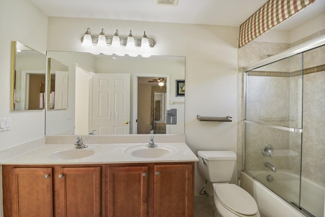 full bathroom featuring a sink, shower / bath combination with glass door, double vanity, and toilet