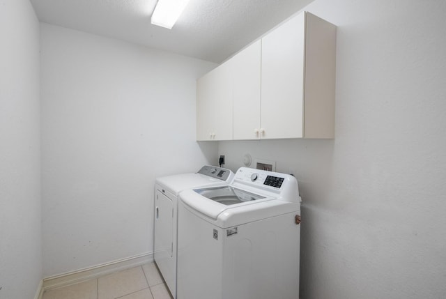 laundry area featuring light tile patterned floors, cabinet space, baseboards, and washer and clothes dryer