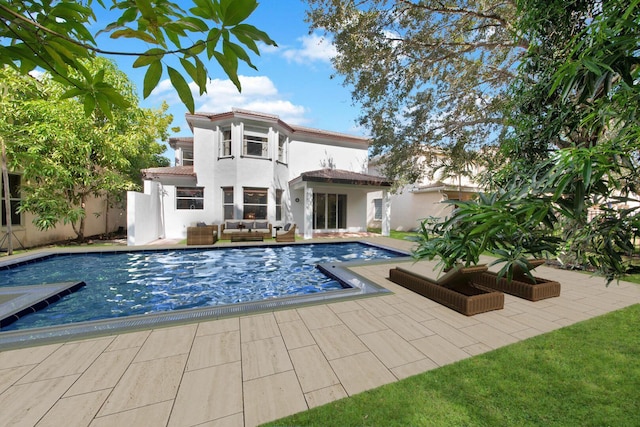 rear view of property with an outdoor pool, stucco siding, an outdoor hangout area, and a patio area