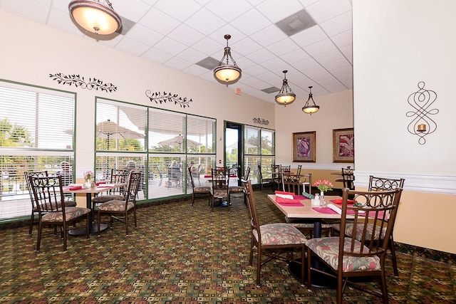 dining area with a drop ceiling and a high ceiling