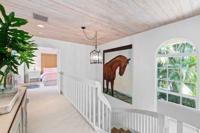 hall with an inviting chandelier, light colored carpet, and wooden ceiling