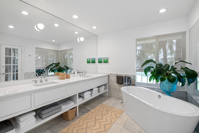 bathroom featuring vanity, tile walls, and a tub to relax in