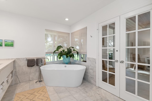 bathroom featuring a bathing tub, tile walls, vanity, and french doors