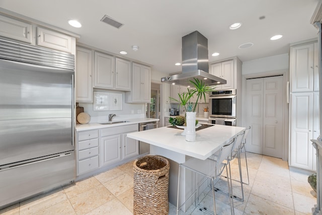 kitchen featuring sink, gray cabinets, appliances with stainless steel finishes, a center island, and island exhaust hood