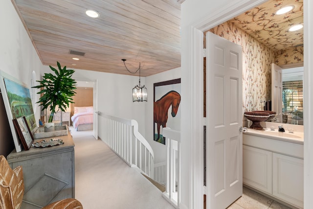 hall featuring wood ceiling, light colored carpet, sink, and a notable chandelier