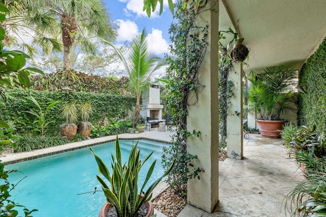 view of swimming pool with an outdoor fireplace and a patio