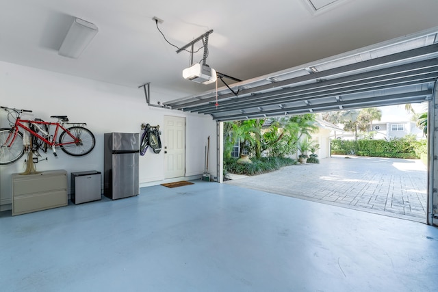 garage with a garage door opener and stainless steel refrigerator