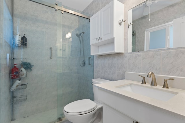 bathroom with a stall shower, tile walls, vanity, and toilet