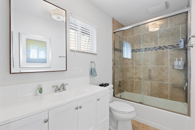 bathroom with shower / bath combination with glass door, vanity, toilet, and tile patterned floors