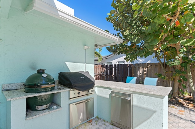 view of patio / terrace featuring fence, exterior kitchen, and area for grilling