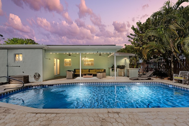 pool at dusk featuring a patio, outdoor lounge area, area for grilling, a ceiling fan, and fence