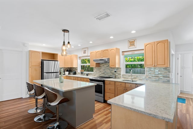 kitchen with a sink, light brown cabinetry, appliances with stainless steel finishes, and a kitchen island