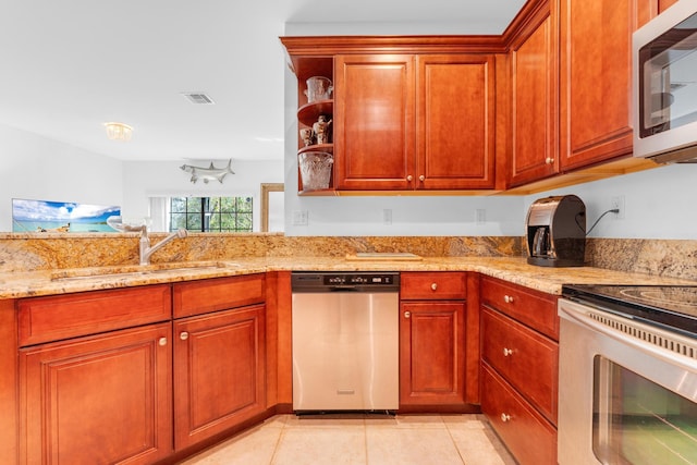 kitchen with appliances with stainless steel finishes, light stone countertops, sink, and light tile patterned floors